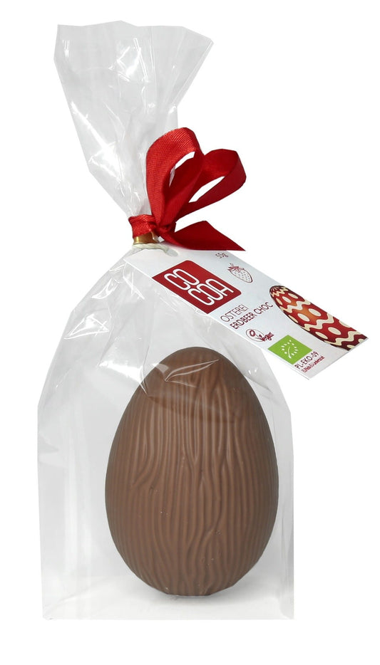 Bio Erdbeerei mit Erdbeergeschmack, 55 g, von COCOA, zeigt ein Ei mit Erdbeer-Dekoration und frischen Erdbeeren daneben