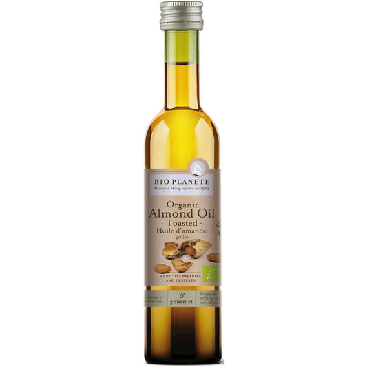 Bio geröstetes Mandelöl in 100 ml Flasche von BIO PLANETE, braune Mandelölflasche mit Mandelkernen im Hintergrund